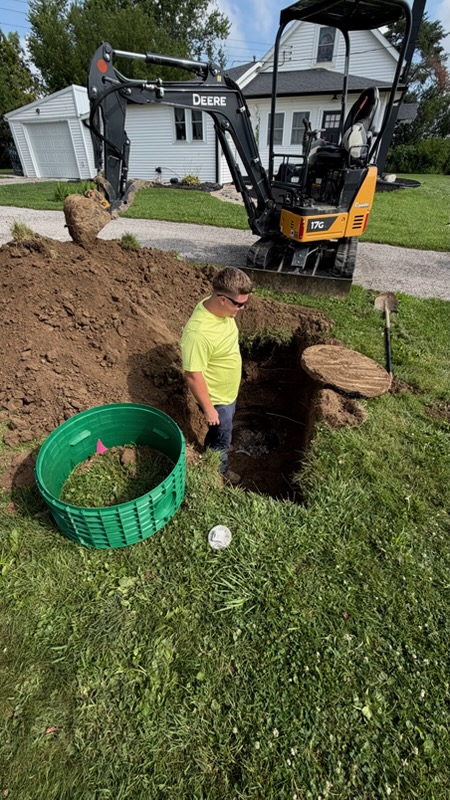 Mac's Septic crew member at a septic tank access excavation with a mini excavator